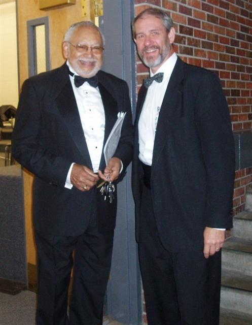 2 men in suits posing for picture